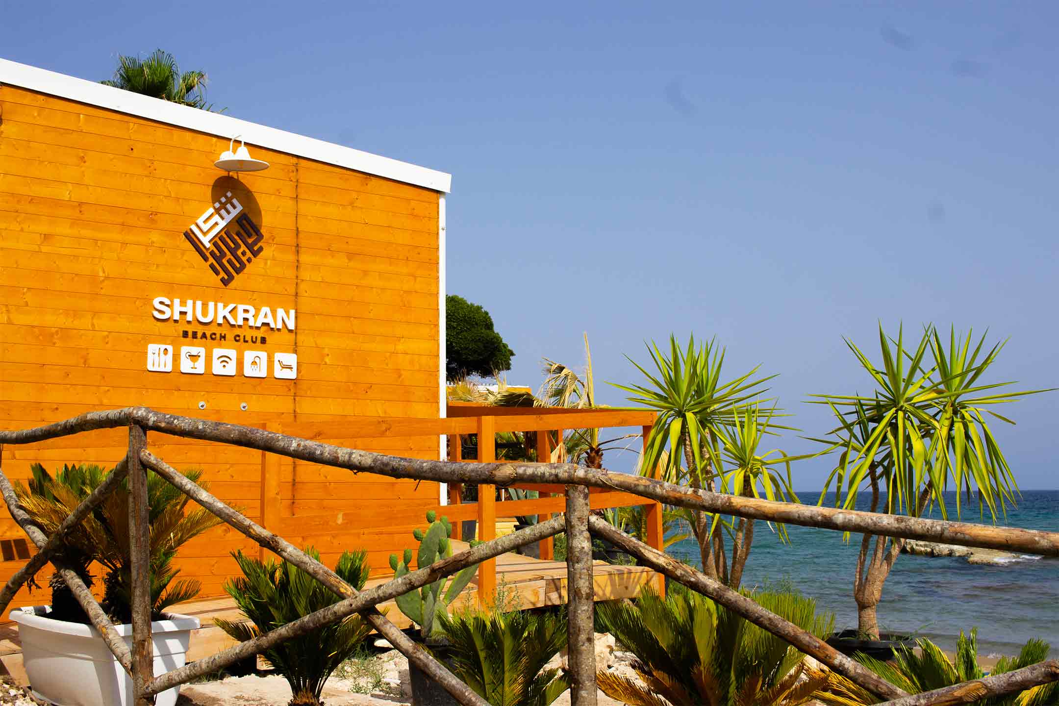 Ingresso del lido con staccionata circondata da piante e verde